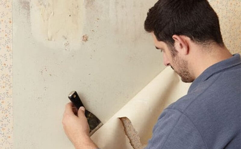 мужчина сдирает обои