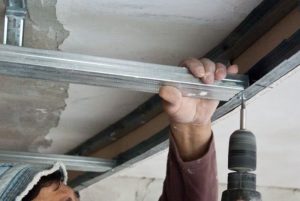 Направляющий профиль необходимо прикрепить к потолку, полу и поместить в углы стен
