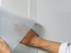 Полотно прикладывают к верхнему краю стены и разглаживают, прочно прижимая к поверхности